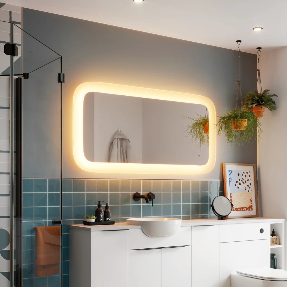 Lifestyle image of the hib. Cassini Curve 1200mm x 700mm Deep Border LED Mirror mounted above a inset basin and countertop bathroom furniture